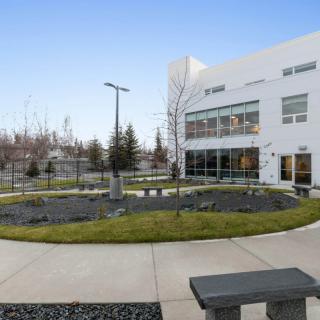 A modern building with an outdoor courtyard featuring benches and landscaping.