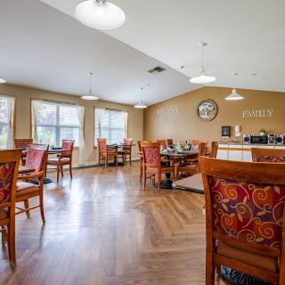 A cozy dining area with neatly arranged tables and chairs, featuring warm lighting and elegant decor.