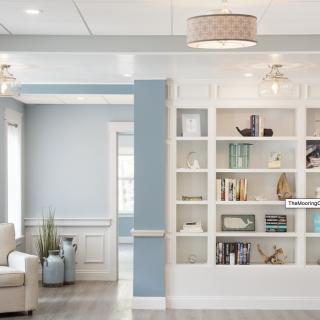 A modern living room with a blue and white color scheme, featuring a built-in bookshelf and comfortable seating.