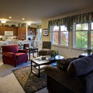A cozy living room with a view into the kitchen, featuring comfortable seating and natural light.