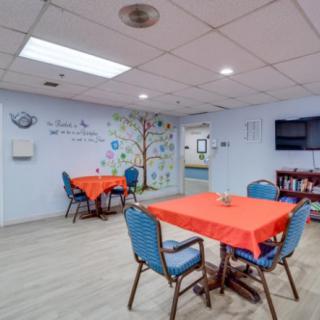A brightly lit communal dining area with tables covered in red cloths and a decorated wall.