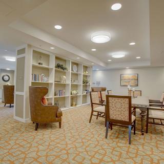 A spacious and well-lit living room with bookshelves and a dining area.