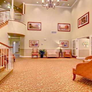 A spacious lobby with elegant furniture and artwork, featuring a grand staircase and chandelier.