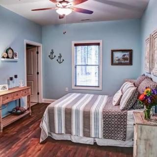 A cozy bedroom with blue walls, a striped bedspread, and wooden flooring.
