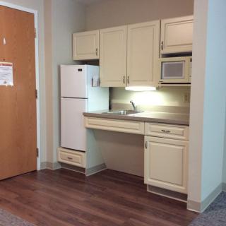 A small kitchenette setup with a fridge, sink, and microwave.