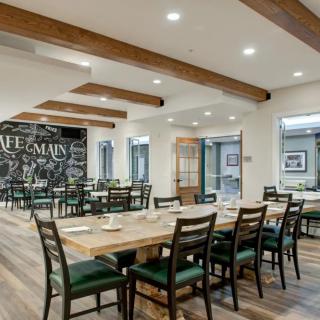 A modern restaurant interior with wooden beams and neatly arranged tables and chairs.