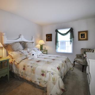 A cozy bedroom with a floral-themed bedspread and classic decor.