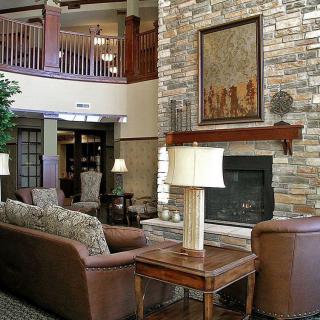 A cozy lounge area featuring a stone fireplace, comfortable sofas, and elegant table lamps.