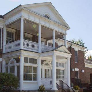 A two-story house with a prominent porch and classical columns.