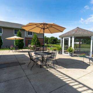 A sunny patio area with outdoor seating, umbrellas, and a gazebo.