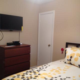 A cozy bedroom with a wall-mounted TV and a neatly arranged bed.