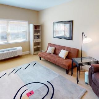 A cozy living room with a sofa, floor lamp, and bookshelf by the window.