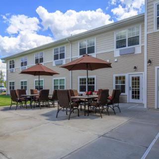 A patio area with tables and umbrellas outside a two-story building.