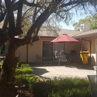 A sunny backyard patio with a red umbrella and outdoor seating.