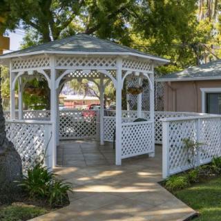 A charming white gazebo with lattice design nestled in a garden setting.