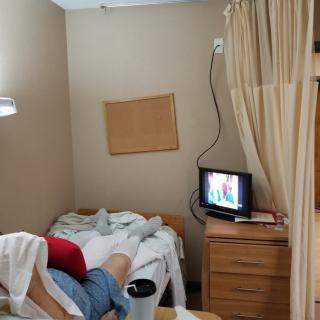 A hospital room with a bed, television, and privacy curtain.