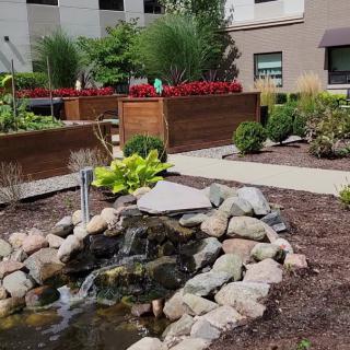 A beautifully landscaped garden with a small pond surrounded by rocks and vibrant flower beds.
