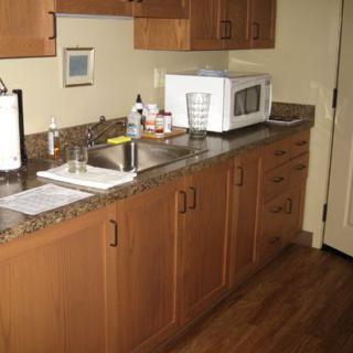 A kitchen area featuring a microwave on a countertop with wooden cabinets and a sink.