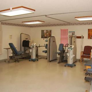 A physical therapy clinic equipped with various exercise machines and chairs for rehabilitation exercises.