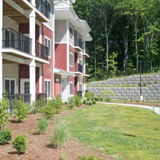 A modern apartment building with landscaped surroundings and green grass.
