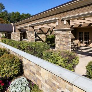 Modern building with stone columns and lush landscaping.