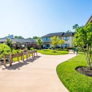 A bright and sunny residential area with landscaped gardens and a winding pathway.