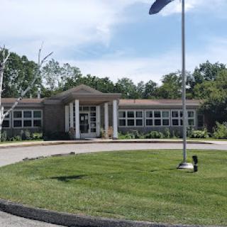 A sunny day at the school building, featuring well-maintained grass and a flagpole.