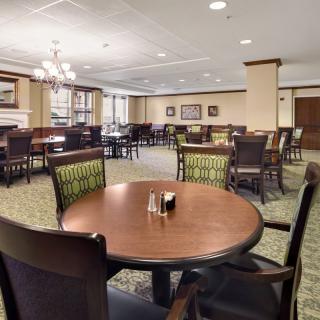 A spacious dining area with neatly arranged tables and chairs, featuring elegant lighting fixtures.