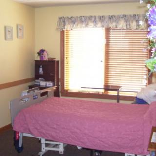 A hospital room featuring a single bed and a window with blinds.