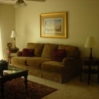 A cozy living room with a sofa, lamps, and a framed painting on the wall.