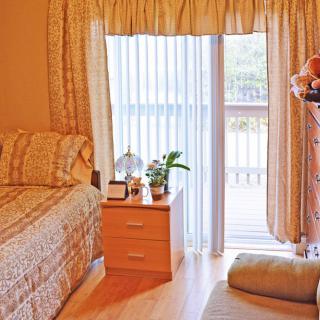 A cozy bedroom with a bed, nightstand, and large window draped with curtains.