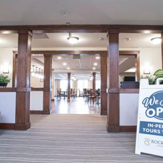 A welcoming lobby area with an open sign and wooden pillars leading to a spacious room.
