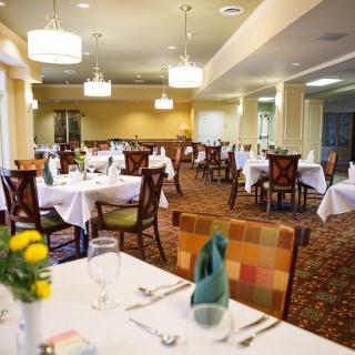 A warmly lit restaurant dining area with neatly arranged tables and chairs.
