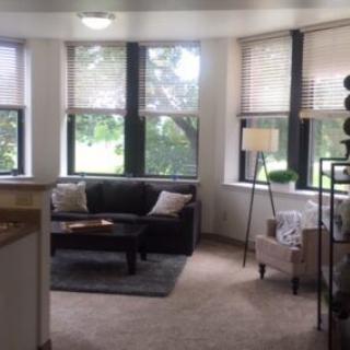 A cozy living room with a sofa, armchair, and large windows.