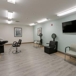 A modern salon interior with chairs, hair dryers, and a waiting area.