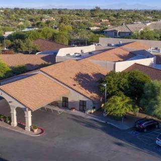 Aerial view of a suburban building with a parking lot and surrounding trees.