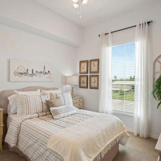 A bright and cozy bedroom with minimalist decor, featuring a neatly made bed and sunlight streaming through the window.