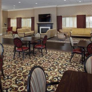 A hotel lobby with patterned carpet, multiple seating areas featuring sofas and tables, a fireplace, and a television.