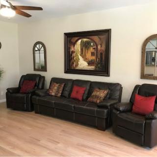 A cozy living room featuring a leather sofa adorned with decorative pillows, framed artwork on the wall, and stylish mirrors.
