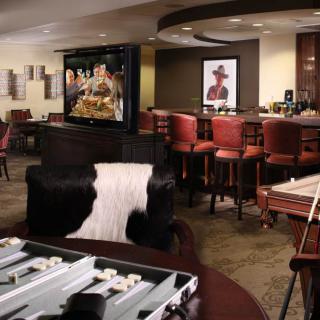A cozy bar lounge featuring a cowhide chair, backgammon table, and a television.