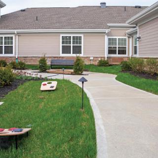 A well-maintained outdoor space featuring a concrete pathway, grassy areas, and recreational games.