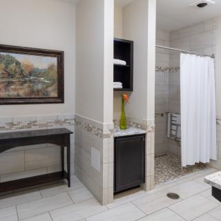 A modern bathroom featuring a walk-in shower with a white curtain, decorative tiles, and elegant furnishings.