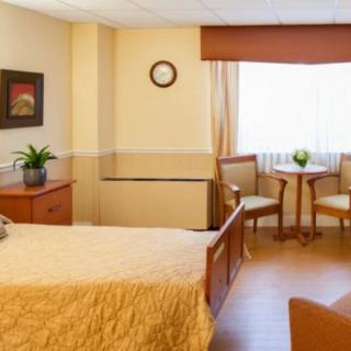 A cozy bedroom with a neatly made bed, a small table with two chairs by the window, and tasteful decor.