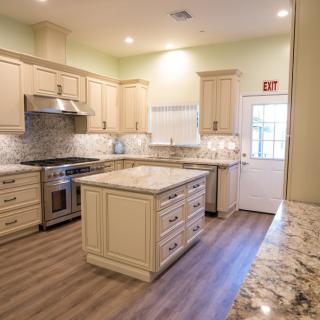 A modern kitchen with an island, cream cabinets, and hardwood flooring.