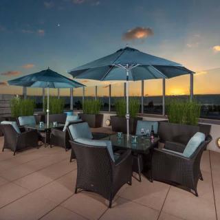 A serene outdoor patio with comfortable seating and umbrellas, set against a beautiful sunset backdrop.