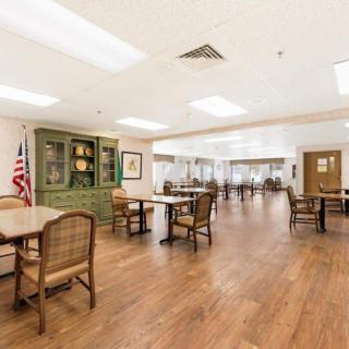 A spacious dining area with wooden floors and several tables and chairs.