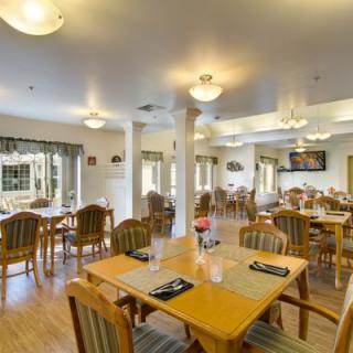 A spacious dining room with wooden tables and chairs, featuring warm lighting and a cozy atmosphere.