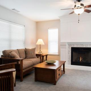 A cozy living room with a sofa, wooden coffee table, lamp, and a fireplace.