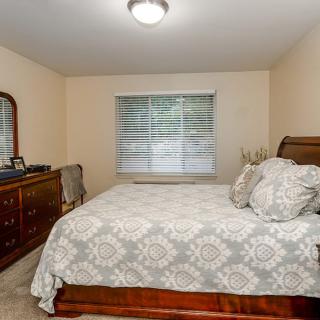 A well-decorated bedroom featuring a bed with patterned bedding, a dresser with a mirror, and a window with curtains.
