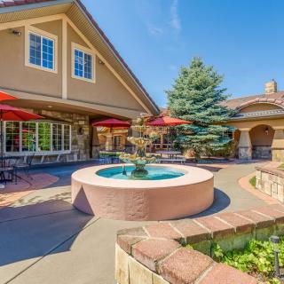 A beautiful patio with a fountain and outdoor seating, surrounded by lush greenery.